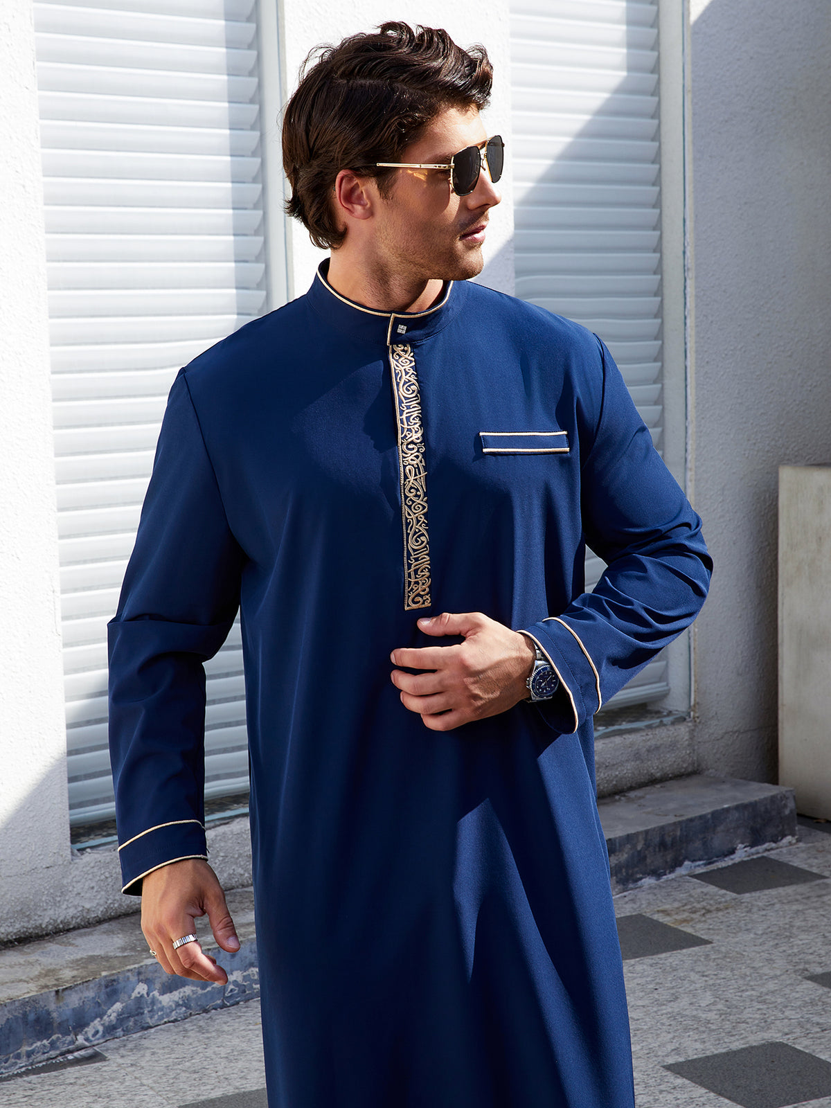 Thobe élégant et moderne pour hommes, avec col droit, patte de boutonnage brodée de motifs géométriques et fausse poche passepoilée, deux coloris disponibles.
